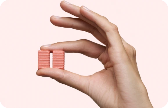 A hand holding two pink wafer biscuits between fingers.